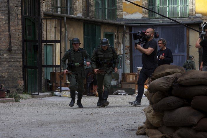 Equipo técnico rodando una escena de calle con actores uniformados