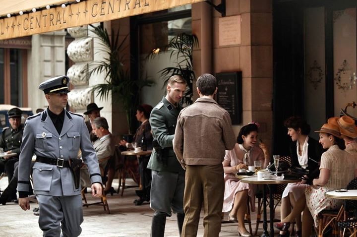 Un oficial y un soldado interrogando a Diego en la terraza de un café