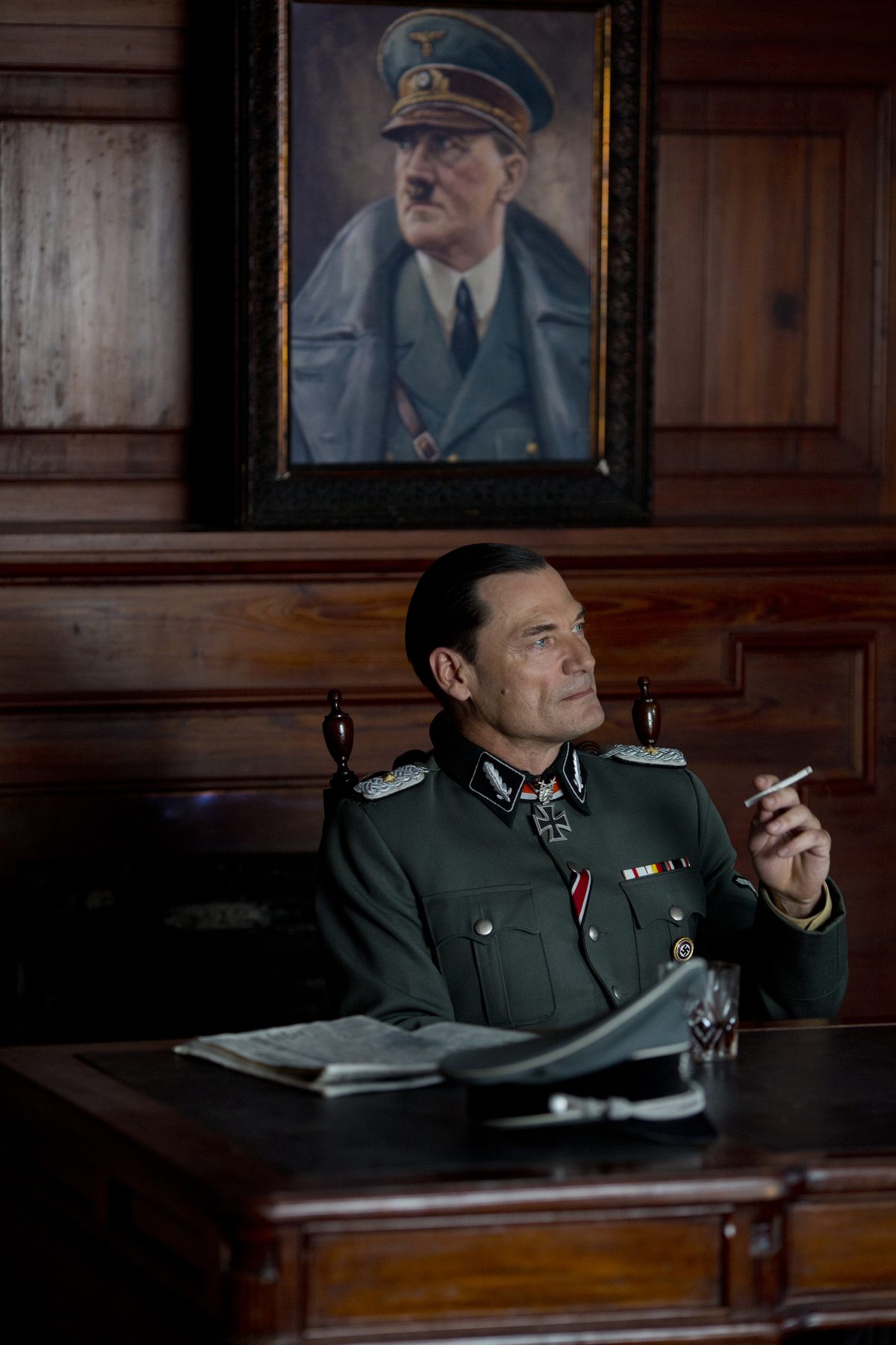 El coronel Maier fumando bajo un retrato oficial nazi